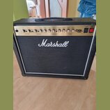 Kytarový kombo zesilovač značky Marshall, model DSL 40C. Má černý potah a bílý lem kolem mřížky reproduktoru. Na horním ovládacím panelu jsou umístěn…