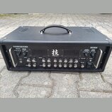 Černý kytarový zesilovač s povrchem imitujícím karbon. Na předním panelu je nápis WAZA AMP HEAD 75, logo BOSS a uprostřed znak s nápisem WAZA CRAFT.…