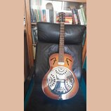 Akustická kytara typu resonator s hnědým gradientním lakem a chromovaným kovovým rezonátorem. Na hlavě hředu je bílý nápis Fender a na těle jsou dvě…