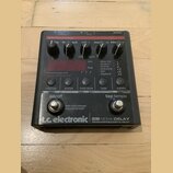 Černý efekt pedál s nápisy „Guitar Effects Technology“ a „tc electronic ND-1 NOVA DELAY PROGRAMMABLE DIGITAL DELAY“. Zařízení má šest ovládacích knof…