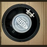 Černý reproduktor s kovovým rámem a připojovacími svorkami. Uprostřed je štítek s nápisy CELESTION, EIGHT 15, GBC-15 a CELESTION INTERNATIONAL LTD. P…