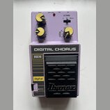 Fialový efekt pedál s nápisem DIGITAL CHORUS a označením DSC10. Na spodní části je černý stupňovací spínač s logem Ibanez. Horní panel obsahuje tři ž…