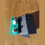 Zelený efekt pedál s nápisy OVERDRIVE, GREEN MILE a MOGER. Má dva ovládací knoflíky označené LEVEL a TONE, přepínač a stoupací spínací tlačítko. Vedl…