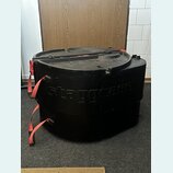 Černý plastový přepravní kufr s červenými popruhy. Na přední straně je vyembasovaný nápis staggcase. Povrch vykazuje běžné známky opotřebení v podobě…