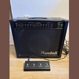 Černý kytarový kombo zesilovač s nápisem Randall na přední mřížce. Na horním ovládacím panelu je uveden model RG50TC a nápis 50 WATT TUBE COMBO. Před…