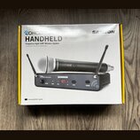 Fotografie znázorňuje krabici s bezdrátovým mikrofonním systémem. Na obalu je nápis CONCERT HANDHELD Frequency-Agile UHF Wireless System a logo SAMSO…