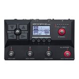 Černý basový procesor značky ZOOM, model B2 FOUR. Zařízení má digitální displej s nápisy Bass Driver PREAMP, DYNAMIC COMPRESSOR a GOAT2018, čtyři ovl…
