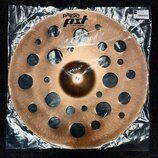 Bronzový činely s mnoha vyvrtanými otvory různých velikostí, zabalený v průhledné plastové fólii. Na povrchu je černý nápis pAiste a logo PST X, pod…