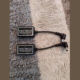 Dvě černé krabičky s napájecími kabely. Na obou je bílý nápis Xotic Effects, California, USA, VOLTAGE DOUBLER a 15Vdc / 18Vdc. Na bocích jsou označen…