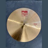 Zlatavý kovový činel s viditelným rýhováním povrchu. Na horní části je červené logo PAiste 2002 s nápisy TRADE MARK a MADE IN SWITZERLAND. V pravé čá…