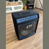 Černý basový kombo zesilovač s modrým ovládacím panelem a kovovou mřížkou. Na horní části je nápis EBS DROME PROFESSIONAL BASS COMBO 750 W a DEVELOPE…