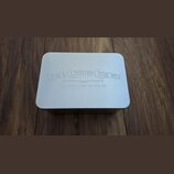 Stříbrná kovová krabička s zaoblenými rohy. Na víčku je vyražen nápis BLACK COUNTRY CUSTOMS a pod ním menší text HANDCRAFTED IN THE UK. Povrch je mat…