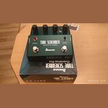 Zelený efekt pedál s kovovým šasi a čtyřmi černými ovládacími knoflíky. Na přední straně je bílý nápis TUBE SCREAMER, Overdrive Pro TS808DX a logo Ib…