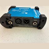 Modrý elektronický přístroj s černým plastovým rámem a nápisy SAMSON a S-monitor. Na zadní straně jsou konektory s popisky THRU, MIC IN, MIC THRU a S…
