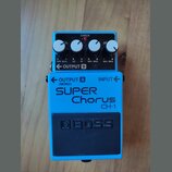 Modrý kytarový efekt s nápisy SUPER Chorus a CH-1. Na spodní části je černý gumový pedal s vyraženým logem BOSS. Horní panel obsahuje čtyři bílé otoč…