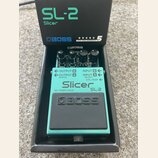 Kytarový efekt Boss SL-2 Slicer v tyrkysovém provedení, umístěný ve své originální černé krabici. Na pedálu jsou viditelné tři ovládací knoflíky a ná…