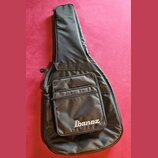 Černý poloměký pouzdro (gig bag) na kytaru. Na přední kapse je bílý nápis Ibanez. Povrch materiálu vykazuje mírné pomačkání a známky používání.