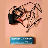 Černý napájecí adaptér s připojenými kabely a několika konektory. Vedle něj je modrá krabička s bílým nápisem CALINE P1 POWER, ISOLATED PROTECTION a…