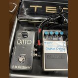 Dvě efektové pedály v černém kufru, propojené kabely. Vlevo je šedý pedál s nápisy „DITTO“, „STEREO LOOPER“, „true bypass“ a logem „tc electronic“. V…