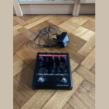 Černý efekt pedál s červeným pruhem a nápisy TC-HELICON harmony GXT a VOICETONE™. Zařízení obsahuje několik ovládacích knoflíků, přepínačů a displej…