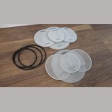 Sada bílých bubnových blan v různých velikostech a tři černé gumové prstence. Pět blan nese nápisy drum-tec a real feel, další čtyři mají nápis Mille…