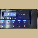 Černý kytarový procesor s nápisem BOSS GT-1000 GUITAR EFFECTS PROCESSOR a označením AIRD. Zařízení má LCD displej, na kterém je zobrazen text P50-1 a…