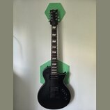 Černá elektrická kytara s dvojsečným stupňovitým hmatníkem a dvěma humbuckery. Na hlavě je bílé logo Ltd. Nástroj je umístěn před dvěma zelenými hexa…