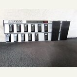 Šedý MIDI kontrolér s nápisem FCB1010 MIDI FOOT CONTROLLER. Zařízení obsahuje dvě řady černých spínacích pedálů s bílými čísly 1 až 10 a tlačítky UP…