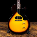 Elektrická kytara s tmelem v provedení sunburst (žlutá až tmhně hnědá). Nástroj má jeden humbucker snímač, černý pickguard a dva zlaté oválné knofíky…