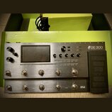 Stříbrný kytarový procesor s nápisem GE 300 a doplňkem Amp modelling & Stomp & Multi Effects. Zařízení má displej, několik otočných ovladačů a řadu s…