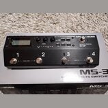 Černý kytarový efektový spínáč Boss MS-3 s kovovým povrchem. Na horní straně je LCD displej, ovládací knoflíky a tlačítka s nápisy LOCK: HOLD > 2 SEC…