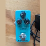 Modrý kytarový efekt s nápisy HYPERGRAVITY a MINI COMPRESSOR. Na horní straně jsou tři černé otočné ovladače s popisky SUSTAIN, ATTACK a LEVEL. Ve sp…