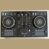 Černý DJ set tvořený dvěma kontrolérymi a centrálním mixérem. Na středovém panelu jsou nápisy PERFORMANCE CONTROLLER DDJ-400, rekordbox a Pioneer DJ.…