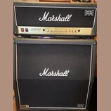 Kytarový zesilovač s boxem značky Marshall. Na hlavě je zlatý panel s nápisem JCM 900 a textem 100W SLP Gain/Bass Reflex Reverb, v pravém horním rohu…
