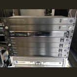 Snímek zachicuje stoh rackových zařízení. V horní části jsou dvě šedé jednotky s nápisem UHF ANTENNA/POWER DISTRIBUTION SYSTEM a logem SHURE UA844. P…