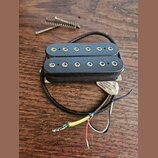 Černý humbucker s dvěma řadami šesti polových magnetů. Na spodní straně je viditelná bílá nálepka s nápisem UNDER ONE OF THE FOLLOWING U.S. PATENTS:.…