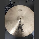 Zlatavý činely s kovaným povrchem. Na horní části je nápis Custom Dark Ride a 22"/56cm, ve spodní části je velké černé logo K. Povrch vykazuje drobné…