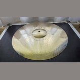 Zlatavý kovový činel s viditelným rýhováním po celém povrchu. Na horní části je nápis "Paiste" a níže označení "Power Crash 16"". Povrch je čistý a b…