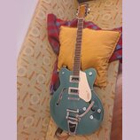 Polodupatá elektrická kytara v tyrkysové barvě s bílým bindingem a krčkem z tmavého dřeva. Na hlavě je nápis Gretsch, na pickguardu je logo GRETSCH a…