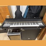 Černý klávesový nástroj s bílými a černými klávesami. Na levé straně je nápis HOHNER a na pravé straně nápis String Performer. V levé části se nacház…