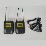 Dvě černé bezdrátové vysílačky s anténami a přiloženým kabelem s konektory. Na levém zařízení je nápis LENS 50, WIRELESS MICROPHONE TX a logo T.R. Sp…