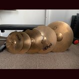 Sada pěti mosazných činelů různých velikostí. Na několika činelech je vidět logo Paiste a označení Zildjian 2002. Povrchy činelů vykazují známky použ…
