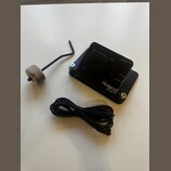 Černý elektronický trigger Roland KD-7 s připojeným kabelem. Na horní části je přepínač POLARITY a vstupy MIX IN a OUTPUT. V doprovodu je imbusový kl…