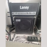 Kytarové kombo tvořené hlavou a kabinetem značky Laney. Na přední straně hlavy je nápis TUBE FUSION TF700 a na kabinetu je náleplka SESSION. Před zes…