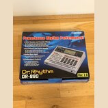 Fotografie znázorňuje originální kartonovou krabici od rytmického automatu. Na krabici je výrazné logo BOSS a nápis Powerhouse Rhythm Performance!. V…