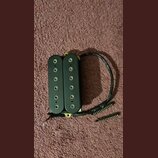 Černý humbucker s dvěma řadami šesti polových magnetů. Na spodní části levého snímače je svisle napsaný nápis DiMarzio. K nástroji vedou černé vodiče…