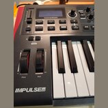 Černý MIDI kontrolér s klávesami. Na horní části je displej a nad ním nápis novation, dále řada tlačítek s popisky jako Template Edit Keyboard, Contr…