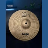 Kruhový mosazný činel s koncentrickým žebrováním povrchu. Na horní části je logo Paiste a nápis ALPHA, ve spodní části je nápis PAiste a pod ním SPLA…