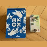 Modrá krabice s bílým nápisem OBNE a textem OLD BLOOD NOISE ENDEAVORS. Vedle ní je bílý kytarový efekt s třemi zelenými knoflíky a jedním posuvníkem.…