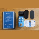 Modře lakovaný efekt pedál s nápisy Blue Rain, Overdrive a True Bypass. Na pedálu jsou tři bílé ovládací knoflíky s popisky VOLUME, TONE a HIGH. Souč…